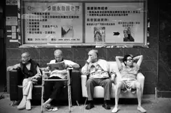 people sitting on bench at bus stop blakc and white