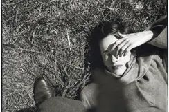 Frau liegt im im Gras und hält sich Hand ins Gesicht, Saul Leiter
