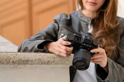 Close-up of a photographer adjusting a Leica camera.