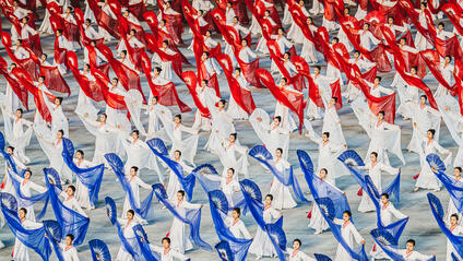 North Korean women dance with hand fans and transparent cloths in white, red and blue.