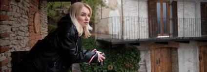 Woman on a balcony holding a camera in her hands.