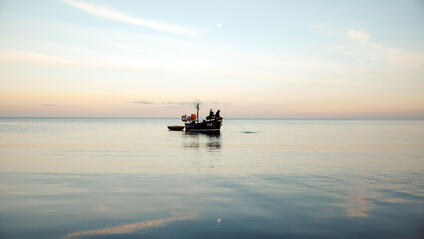 A person in a small boat fishing in the sea.