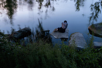 Woman sitting on a stone by the lake