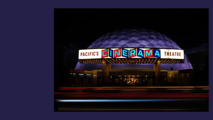 Luminous Cinerama theatre at night.