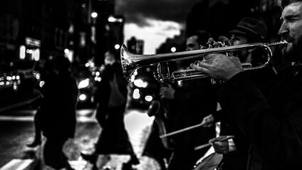 Several musicians and a trumpeter in the foreground play music in the street