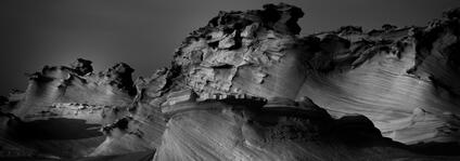 Black and white photography of jagged rock formations in a barren landscape