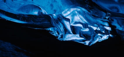 A glowing blue ice formation in a dark cave.