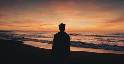 Silhouette of a man watching the sunset on the beach.