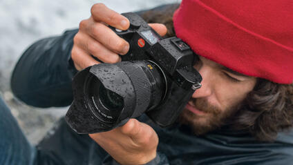 Close-up of a photographer with a red cap looking through the camera