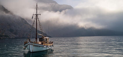 A sailing ship on the sea in front of an island