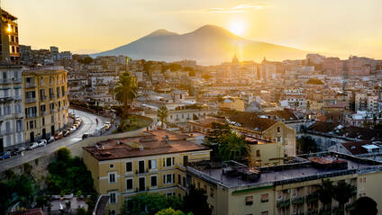 Italian city and the sun setting behind a mountain.