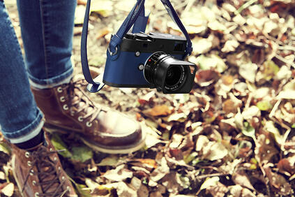 Man in the fall leaves with blue leica camera