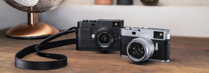 Two Leica cameras on a wooden table.