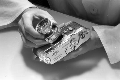 Man mounts lens on Leica M3