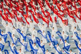 North Korean women dance with hand fans and transparent cloths in white, red and blue. 