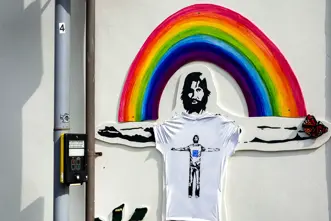 A mural on the wall of a man with outstretched arms in front of a rainbow.