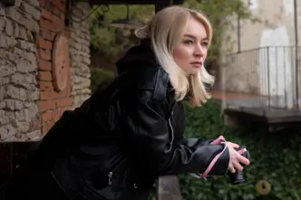 Woman on a balcony holding a camera in her hands.