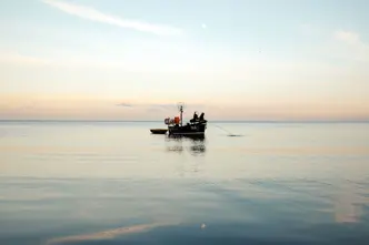 A person in a small boat fishing in the sea.