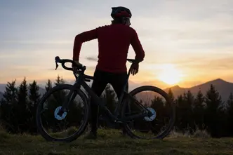 Man leaning on his mountain bike looking at the mountains at sunset.