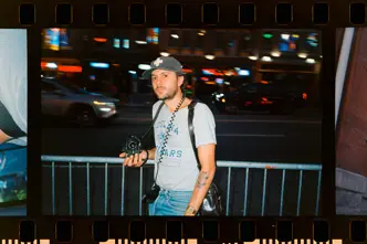 Joe Greer with a Leica M6 in his hand standing at a street at night.