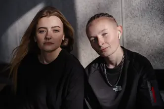 Two women sitting together and looking directly at the camera.
