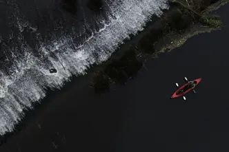 Red canoe paddling along the black sea coast.