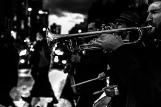 Several musicians and a trumpeter in the foreground play music in the street