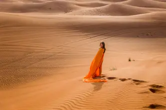 Woman in an orange dress standing in the desert.