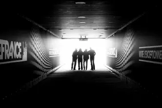 Four people are standing in a stadium tunnel with the sign "Stade France" in the light at the end of the corridor.