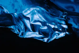 A glowing blue ice formation in a dark cave.