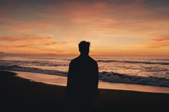 Silhouette of a man watching the sunset on the beach.