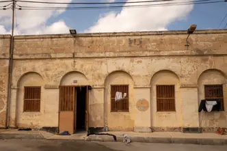 Older stone building with barred windows and clothes hanging outside.