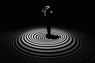 A single person with a hat stands in the centre of concentric circles on a dark background