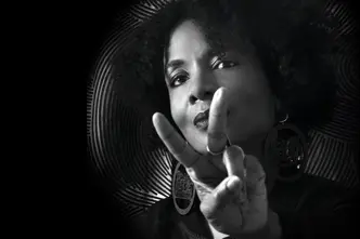 Black and white portrait of a woman with an Afro hairstyle making the peace sign