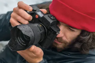 Close-up of a photographer with a red cap looking through the camera