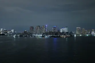 Illuminated skyline of Tokyo at night, with a view of the water in the foreground.