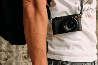 Side shot of a person with a Leica camera hanging in front of his body..