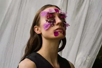 Ein Portrait einer Frau mit Blumen auf ihrem Gesicht.