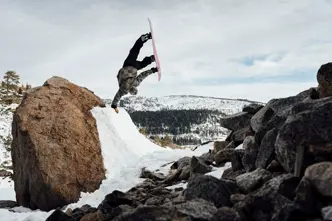 Snowboarder does a one-armed handstand on a ramp in the mountains