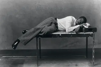 Portrait en noir et blanc de l'acteur Damson Idris allongé sur une table