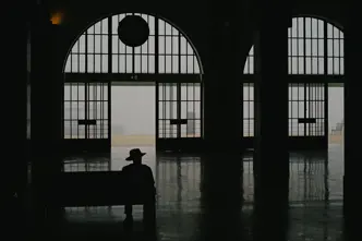 Ombre d'un homme assis dans une gare avec un chapeau