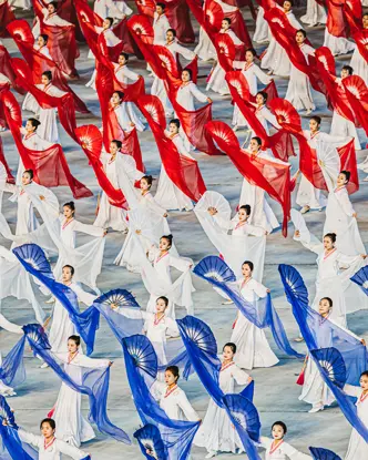 North Korean women dance with hand fans and transparent cloths in white, red and blue. 