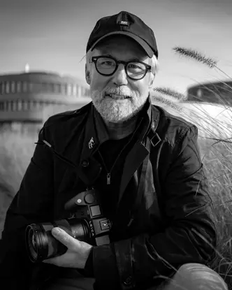Portrait of photographer Ragnar Axelsson holding a Leica camera