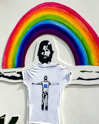 A mural on the wall of a man with outstretched arms in front of a rainbow.