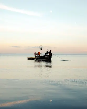 A person in a small boat fishing in the sea.