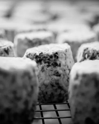 Close-up of a ripening blue cheese on a grid.
