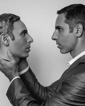 A man holds an artificial head in his hands and looks directly into its eyes.