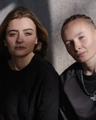 Two women sitting together and looking directly at the camera.