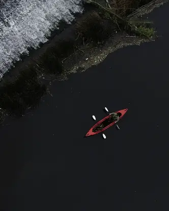 Red canoe paddling along the black sea coast.