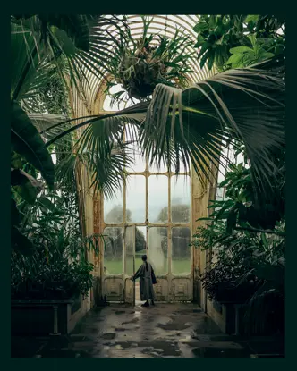A woman in a tropical house opens a large glass door.